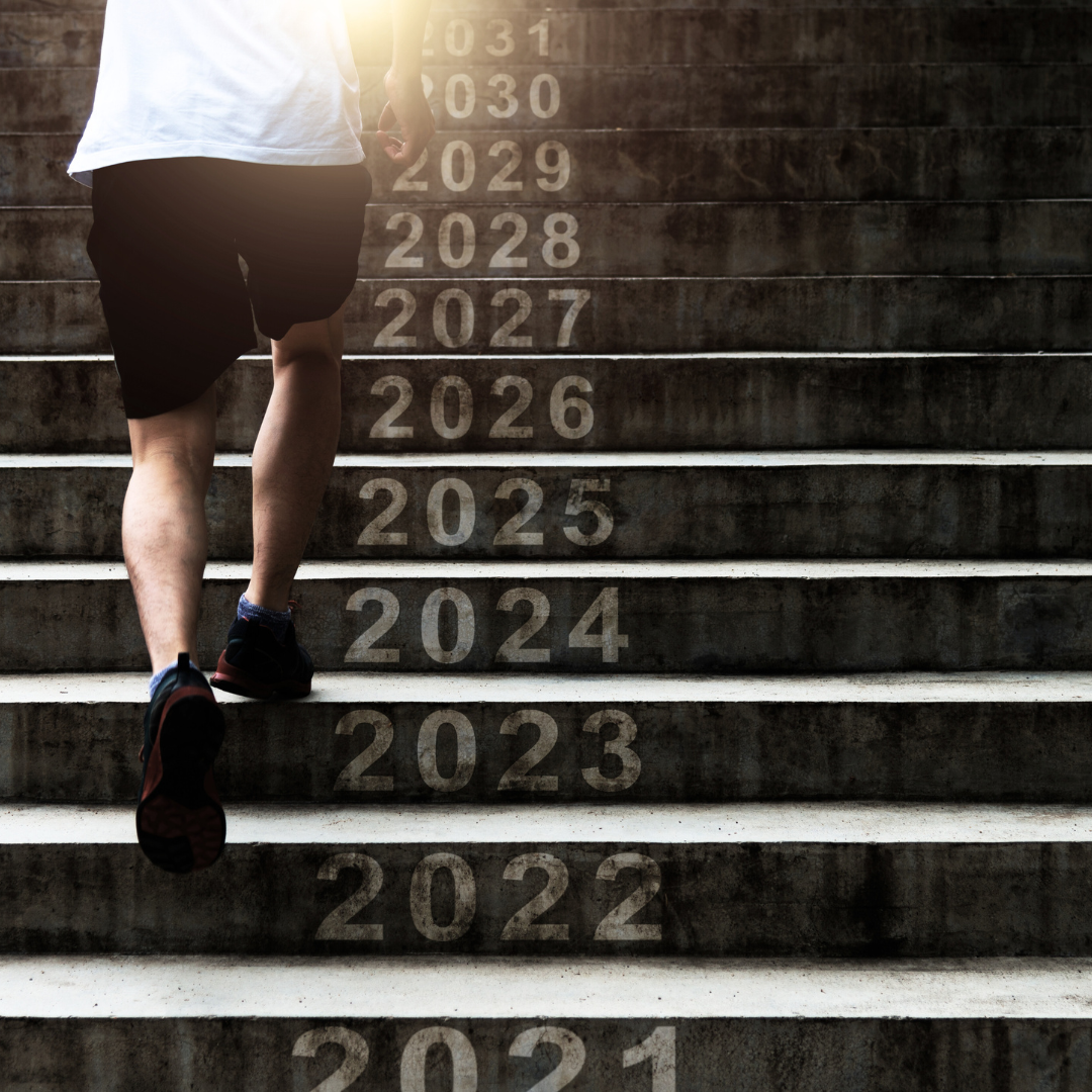 A person walking up a staircase with numbers on each step representing a timeline, indicating a forward moving, growing concept.
